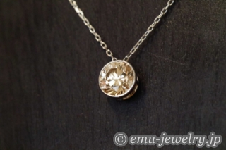 胸元でブラウンダイヤが輝く。